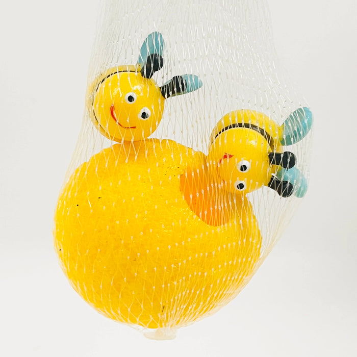 Two smiling yellow toy bees with blue wings and a textured yellow hive inside a white mesh bag.