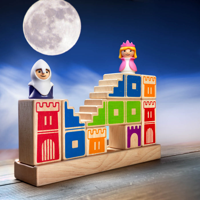 Knight and princess figurines on a colorful wooden block castle with stairs, set against a large moon in a night sky.