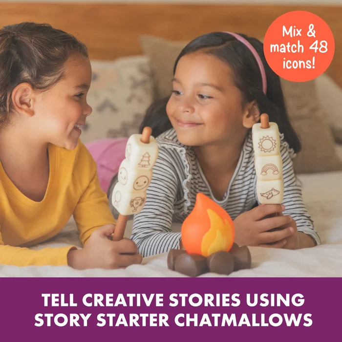 Two girls hold toy sticks with square marshmallows featuring icons over a glowing campfire.