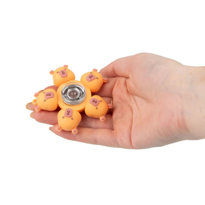Orange fidget spinner featuring five small capybara heads around a silver center, held in a hand.