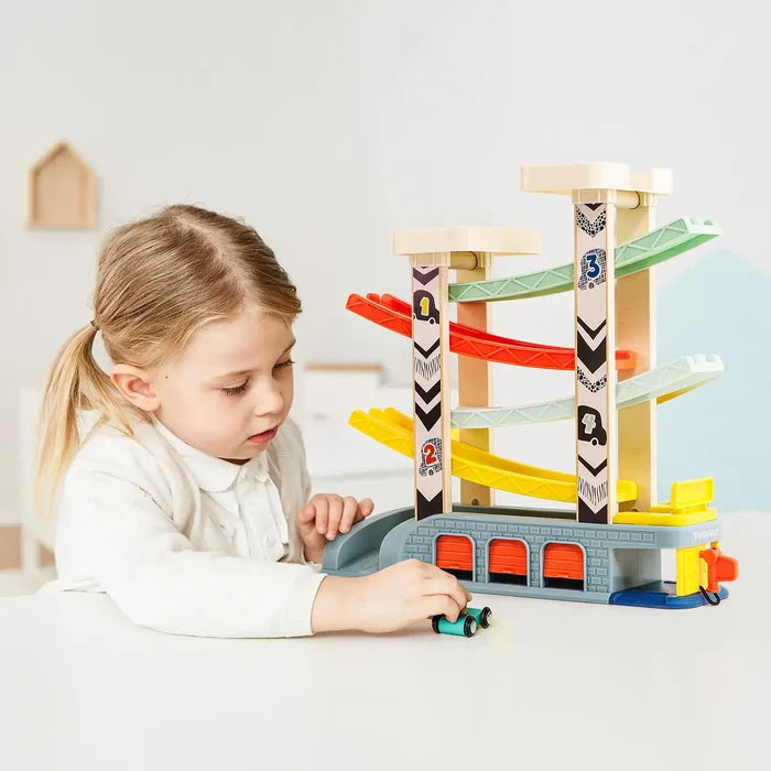 Child playing with a 4-tier wooden car ramp featuring colorful zig-zag tracks, numbered pillars, and a garage base.
