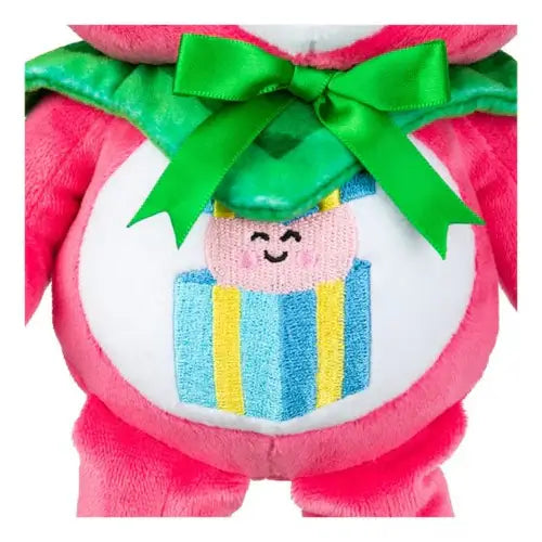 Close-up of pink plush bear with a green bow and an embroidered gift box with a smiley face on its white belly.