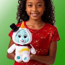 Girl holding a blue Care Bear in a white snowman outfit with a black top hat, carrot nose, and red plaid scarf.
