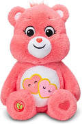 Coral pink plush bear with two smiling hearts on its white belly and a red heart on its foot, sitting front-facing.