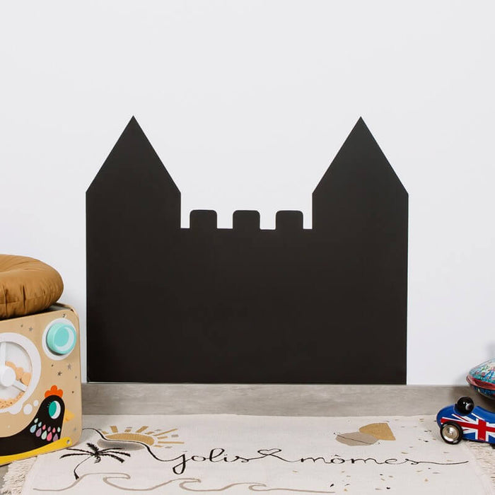 Black castle-shaped magnetic chalkboard with two pointed towers and notched wall, mounted on a white nursery wall.