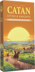 Orange Catan expansion box featuring a knight on horseback riding toward a coastal castle at sunset.