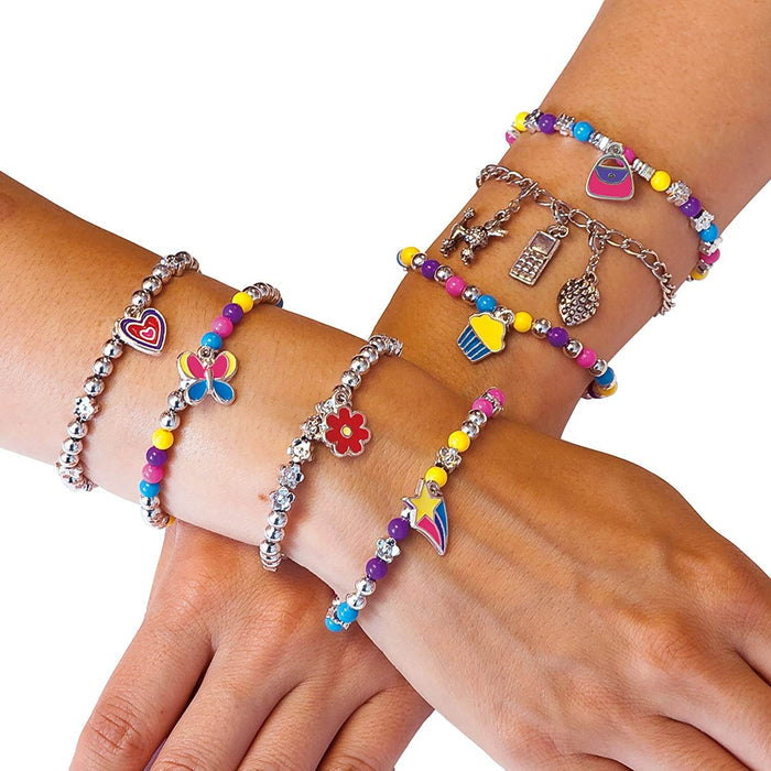 Arms wearing colorful beaded and silver chain bracelets with heart, butterfly, star, cupcake, and dog charms.