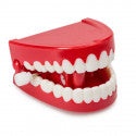 Red plastic gums and white teeth toy with a white wind-up key on the side, angled on a white background.