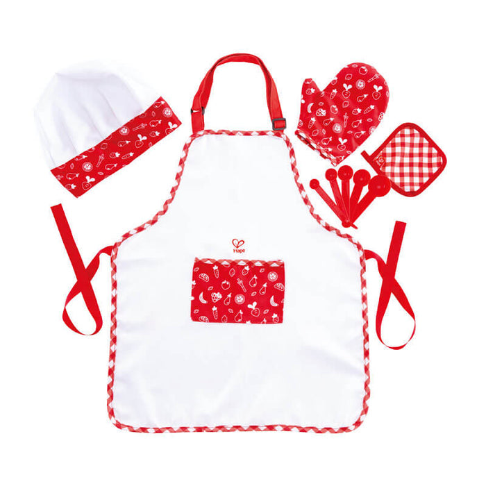 White toy apron with red trim and pocket, matching chef hat, patterned oven mitt, potholder, and measuring spoons.