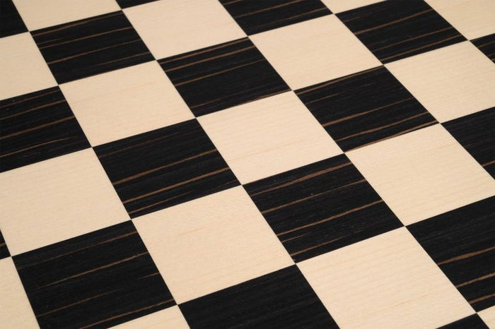 Close-up of a wooden chessboard featuring alternating light beige and dark black squares with visible wood grain.