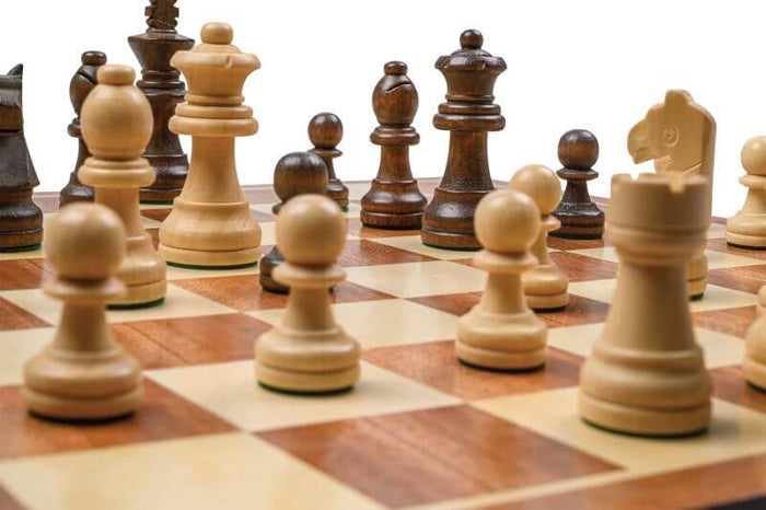 Close-up of light and dark brown wooden Staunton chess pieces on a matching checkered game board.