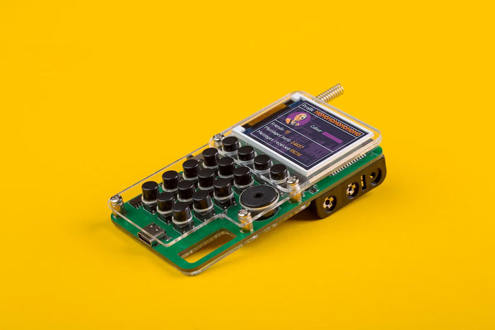 Green DIY electronic device with black buttons, a color screen, and clear acrylic housing on a bright yellow background.