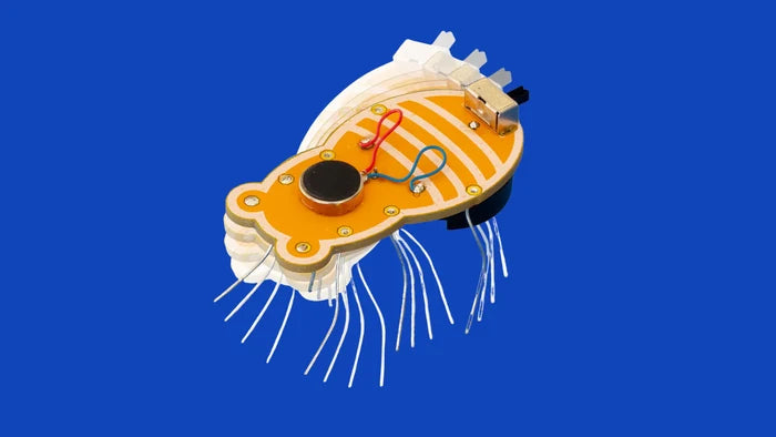 Orange bee-shaped circuit board robot with silver wire legs and colorful wires against a solid blue background.