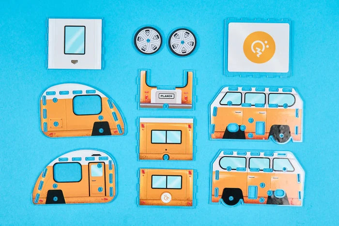 Flat yellow and white plastic components for a DIY model camper van and trailer kit on a blue background.