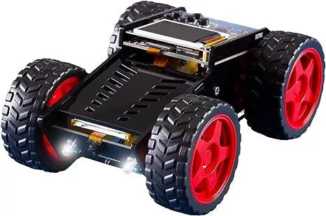 Small black DIY robot car with chunky red-rimmed tires, an LCD screen on top, and bright glowing LED headlights.
