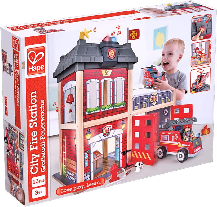 Boxed 3-story red brick wooden fire station toy featuring a ladder truck, helicopter, firefighter, and dalmatian dog.