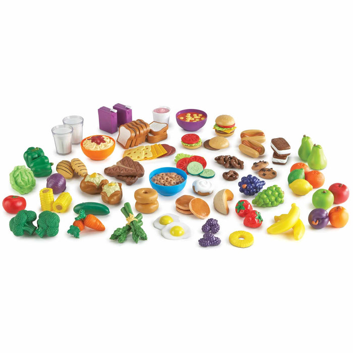 Assorted colorful plastic toy foods including fruits, vegetables, proteins, and snacks on a white background.