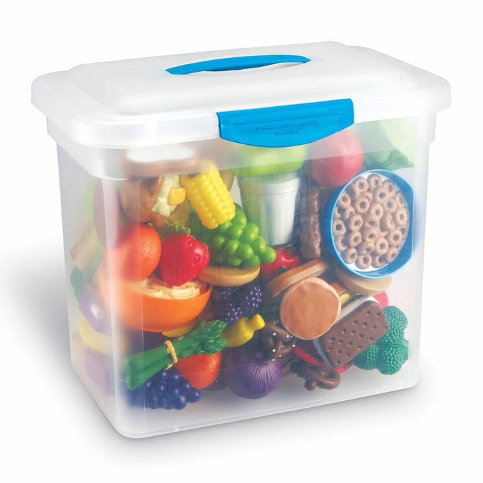 Clear plastic storage bin with blue latches filled with colorful toy fruits, vegetables, and assorted snacks.