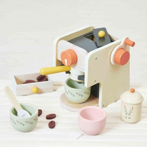 Cream and orange wooden toy espresso maker with floral patterned cups, toy coffee beans, and a sugar bowl.