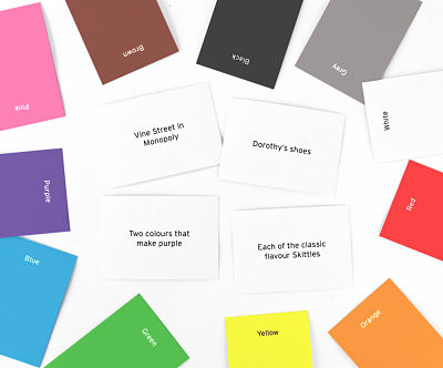 Colorful rectangular cards and white trivia question cards scattered on a plain white surface.