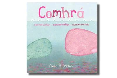 Book cover with a large pink whale and small green whale facing each other beneath the title Comhrá in pink cursive.