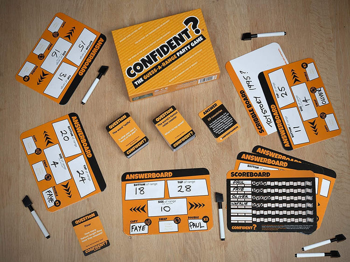 CONFIDENT? party game components, including orange dry-erase answer boards and question cards, on a wooden surface.
