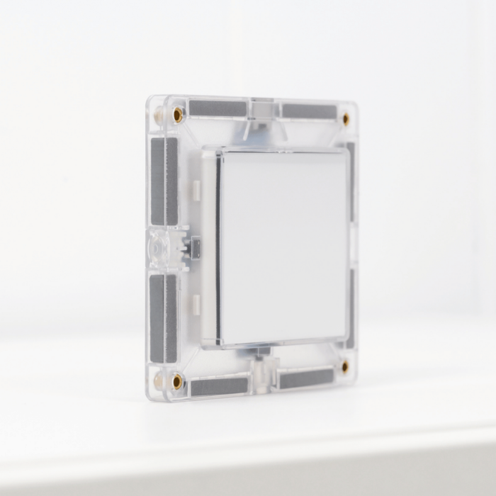 Clear square magnetic building tile with internal LED light components on its edge, standing on a white surface.