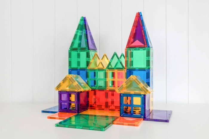 Translucent rainbow magnetic tiles built into a large castle with towers and window shapes on a white background.