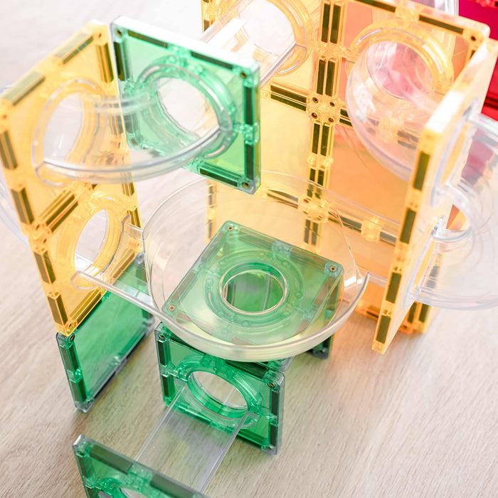 Yellow, green, and orange magnetic square tiles with clear plastic tubes and bowls built into a ball run.