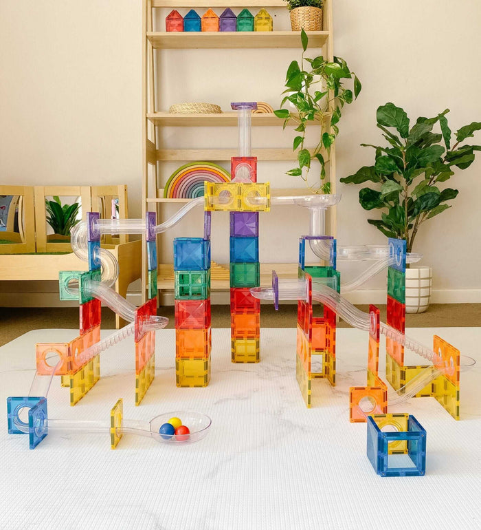 Colorful rainbow magnetic tile ball run with clear plastic tubes and towers, including three small toy balls.