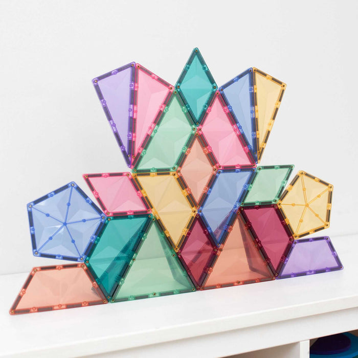 Pastel translucent magnetic tile structure with pentagons, triangles, and trapezoids on a white surface.