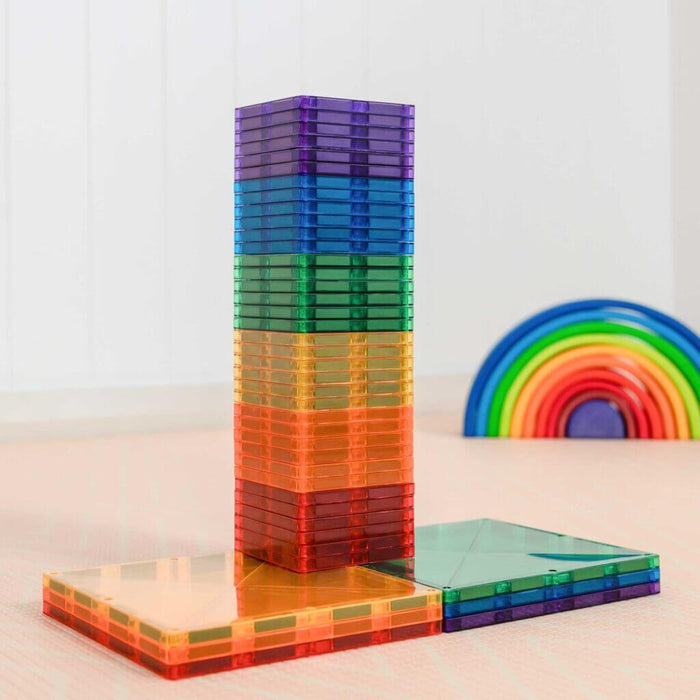Tall tower of translucent magnetic square tiles in rainbow colors, with additional flat stacks on the ground.
