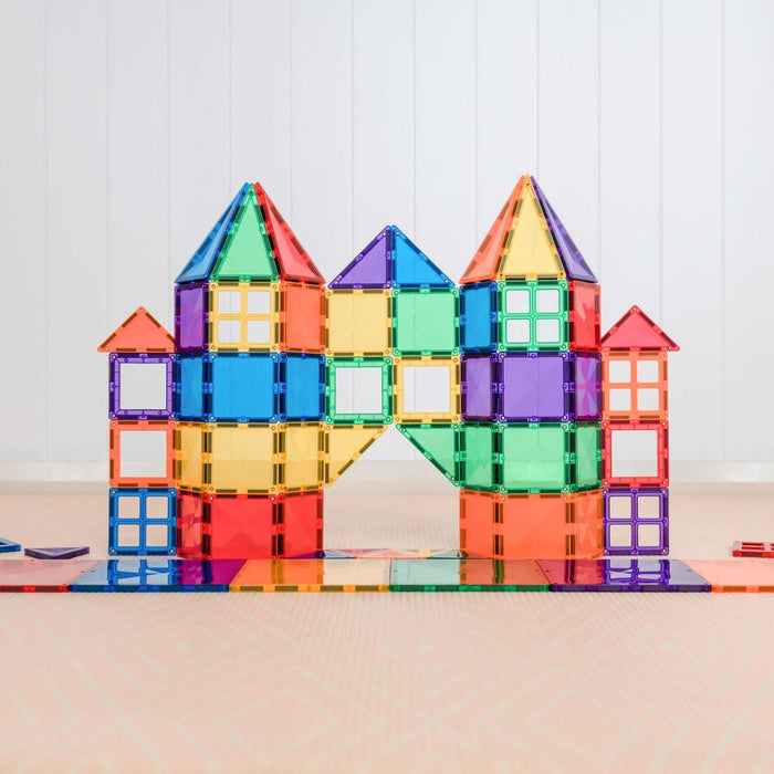 Toy castle with towers and windows built from colorful, translucent magnetic squares and triangles in rainbow hues.