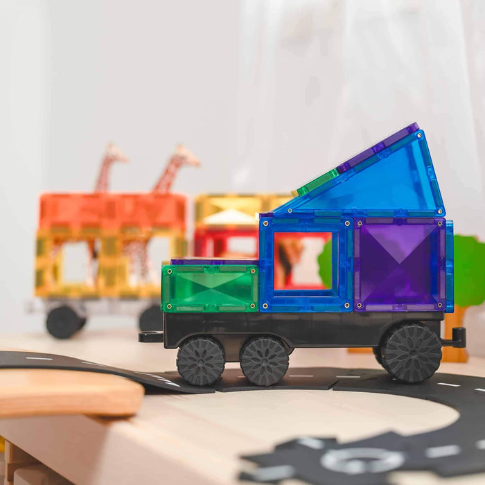 Translucent magnetic tile truck and orange giraffe transport on black wheel bases on a toy road.