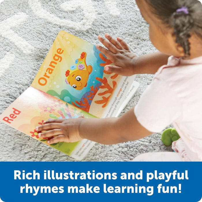 Child reads a board book open to vibrant red and orange pages featuring playful illustrations of a hedgehog and fish.
