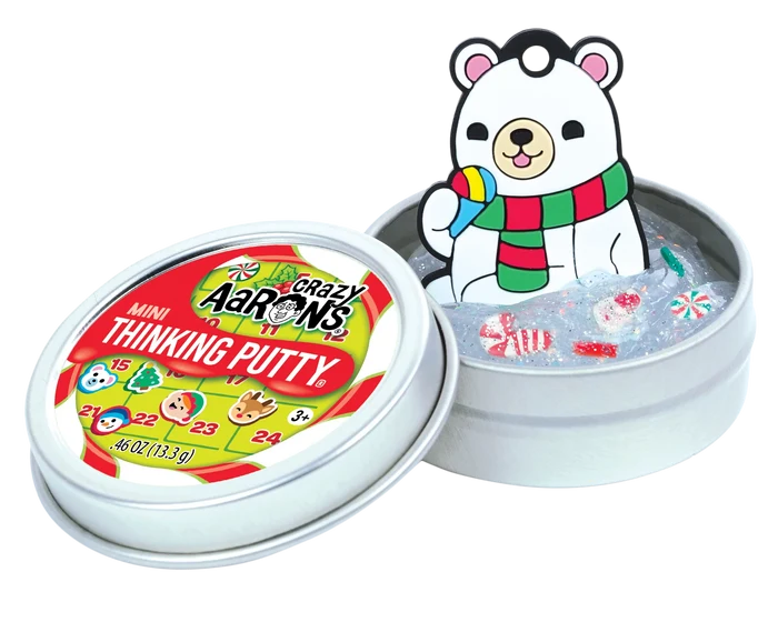 Open tin of clear glittery putty with candy charms, polar bear cutout, and festive advent calendar lid.
