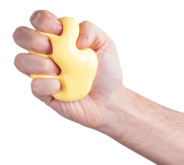 Hand squeezing smooth, pale yellow putty that bulges between fingers against a white background.