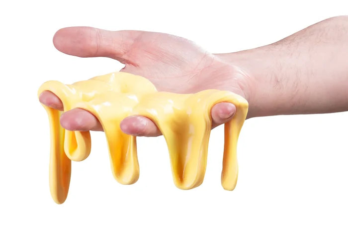 Bright yellow, buttery-textured putty stretching and dripping through the fingers of an open hand.