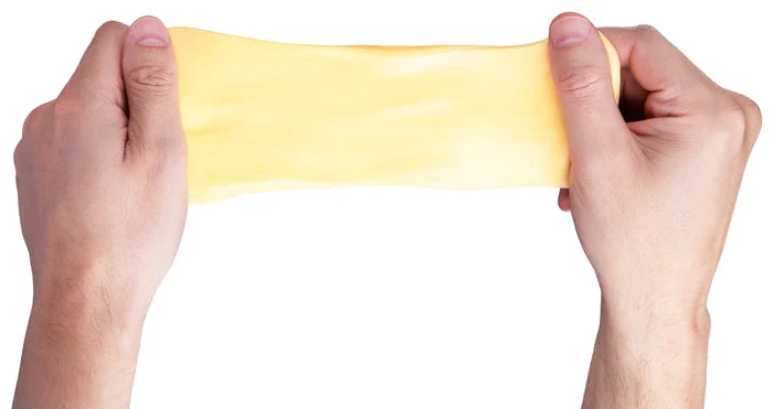 Two hands stretch a wide piece of smooth, bright yellow, elastic putty against a plain white background.