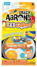 Yellow toy packaging for egg-themed putty with cartoon egg art and a round tin featuring a realistic fried egg graphic.