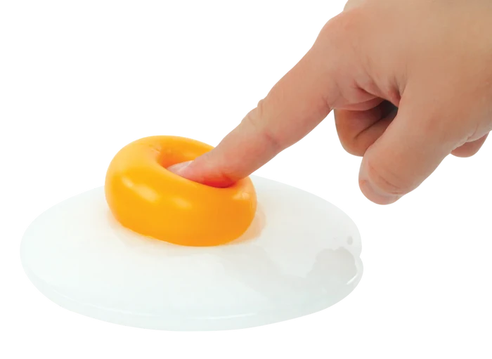 Hand pressing a finger into a squishy yellow yolk on a translucent white egg-shaped putty.