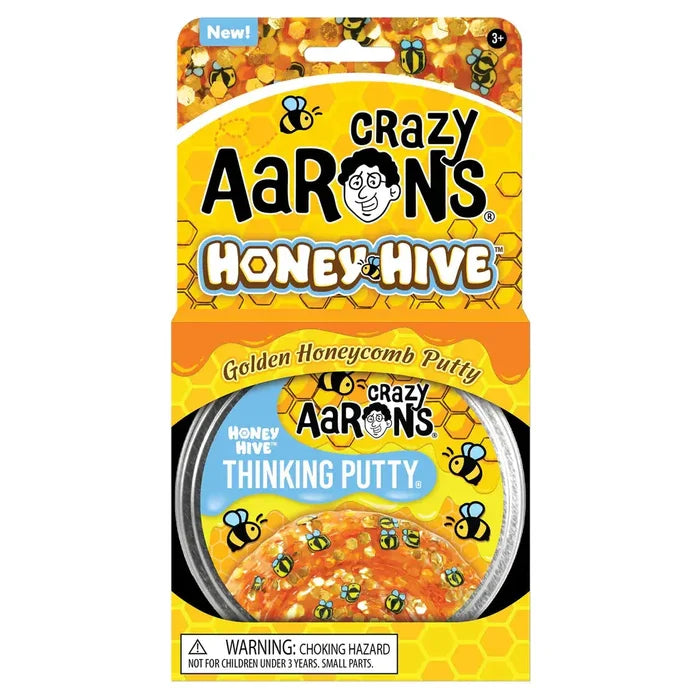 Golden translucent putty with bee charms in a tin, inside a honeycomb-patterned yellow box with cartoon bees.