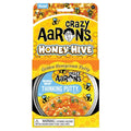 Golden translucent putty with bee charms in a tin, inside a honeycomb-patterned yellow box with cartoon bees.