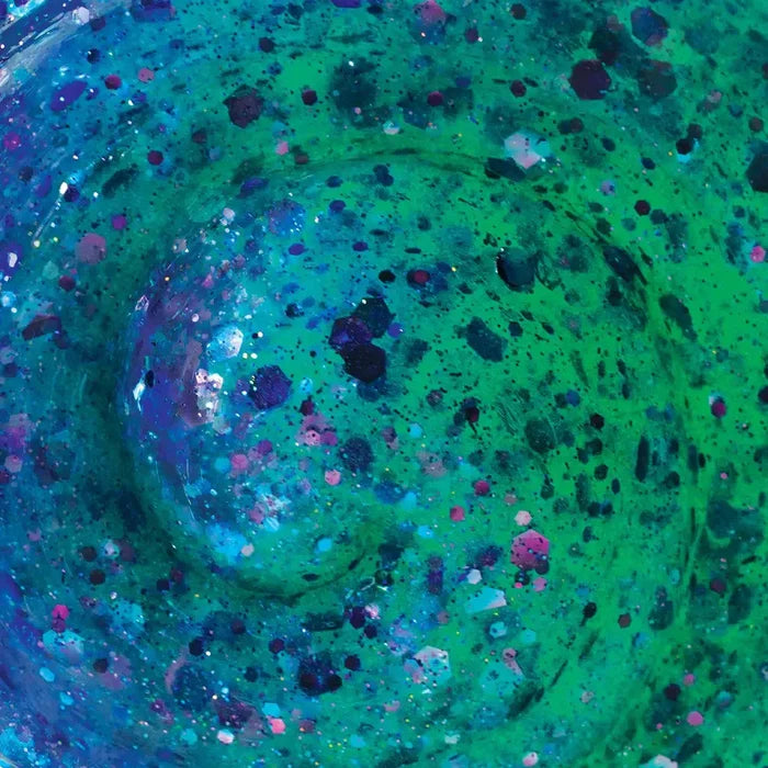 Close-up of swirled teal and green putty filled with pink, purple, and blue chunky hexagonal glitter.