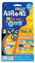 Crazy Aaron's Mac N Cheese putty kit in blue and orange packaging with a tin, mix-ins, and yellow noodle charms.