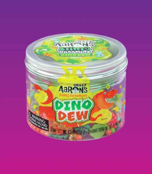 Clear plastic jar filled with colorful slime and charms, featuring a dinosaur label on a purple backdrop.