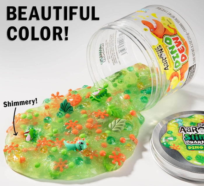 Shimmery green slime with orange beads and dinosaur charms spilling out of a clear jar.