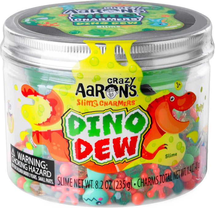Clear jar with silver lid containing green slime and colorful charms. Label shows cartoon dinosaurs and bold text.