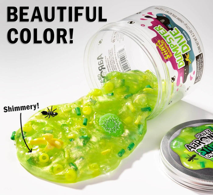 Shimmery green slime spills from a clear jar, filled with toy trash charms like a fly, banana peel, and kiwi slice.
