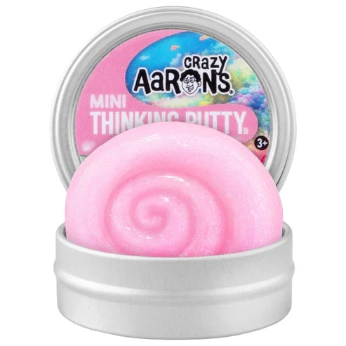 Shimmery pink putty swirled in a small metal tin with a colorful branded lid standing behind it.